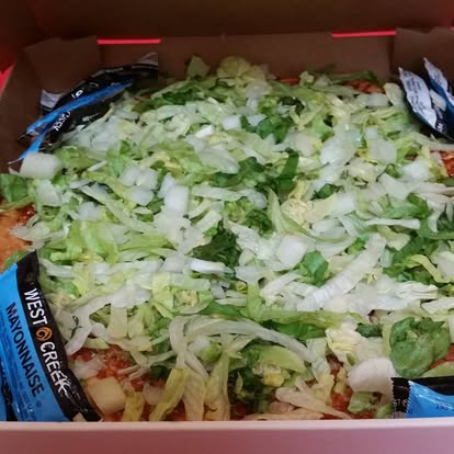 Taco pizza piled high with lettuce